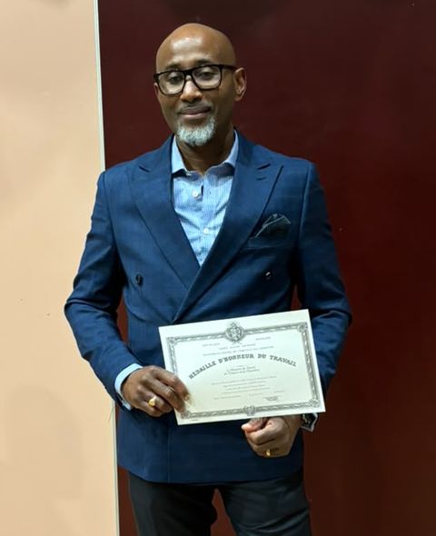 Manfred en veste croisée bleue, diplôme en main